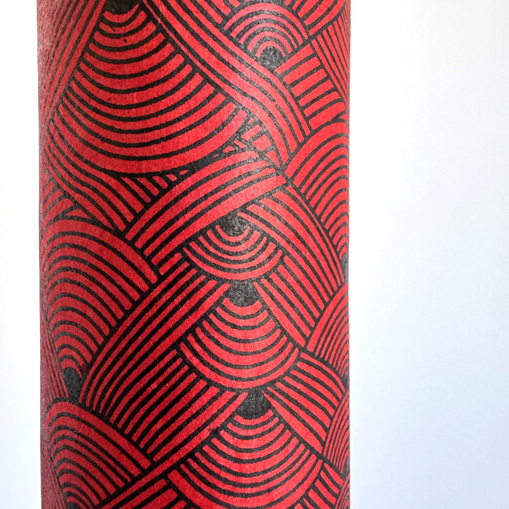 Nepalese handmade decorative lokta paper sheet with a fine lined black knots pattern screen printed on a red lokta paper. Close up