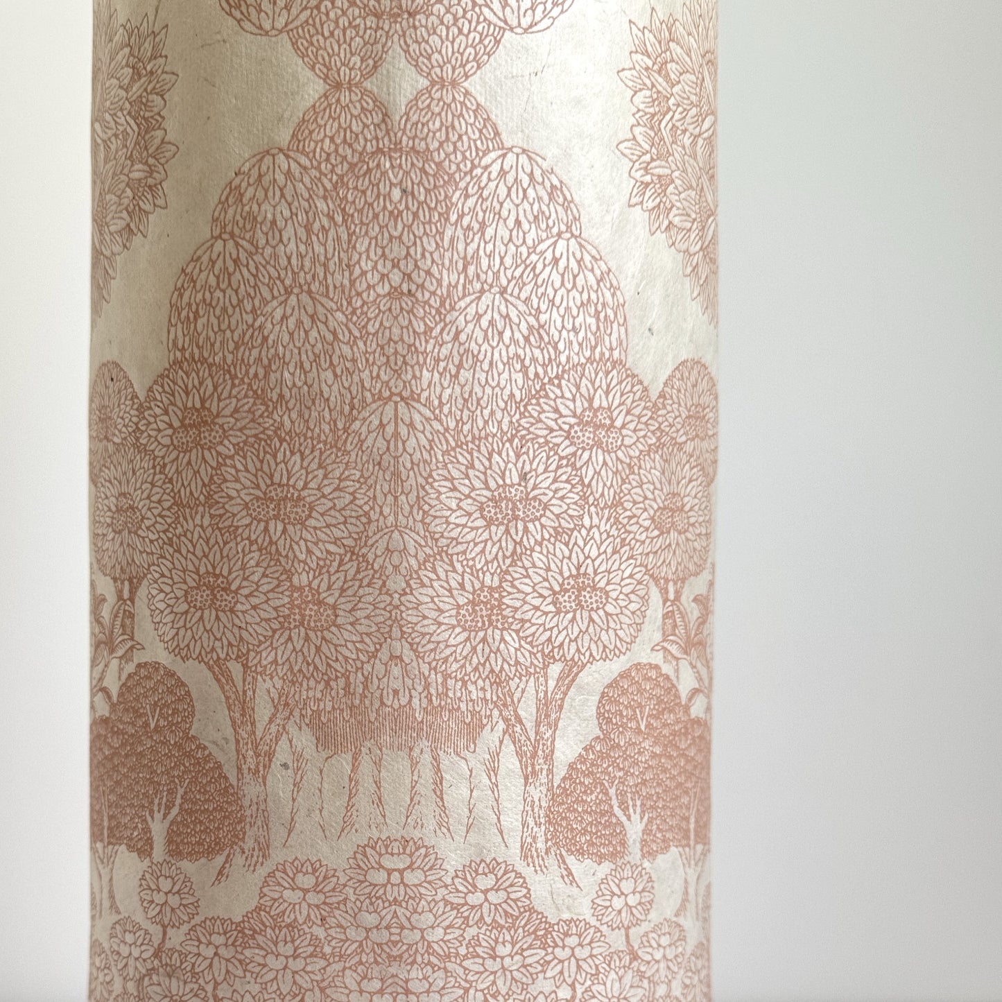 Nepalese handmade decorative lokta paper sheet with a detailed design of trees and flowers in blush pink screen printed on an ivory lokta paper. Close up