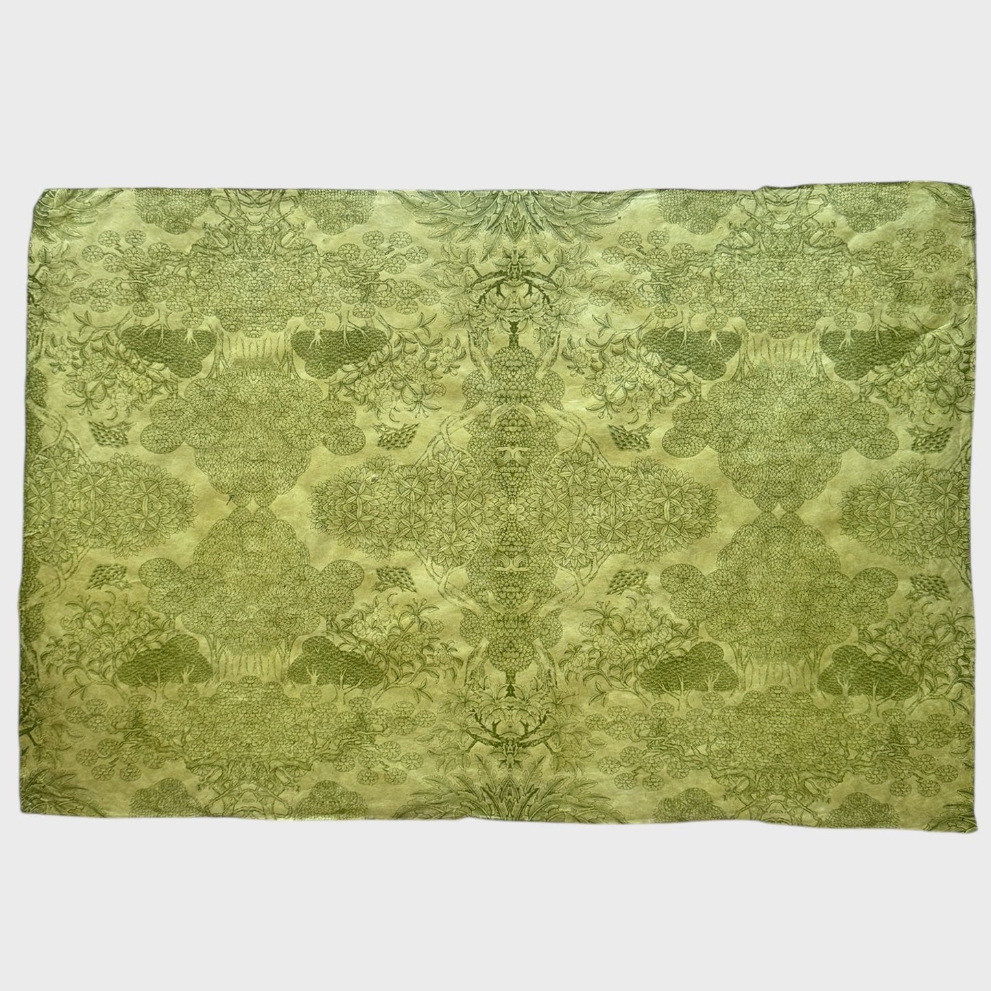 Nepalese handmade decorative lokta paper sheet with a detailed design of trees and flowers in dark green screen printed on a green lokta paper. Full sheet of paper pictured