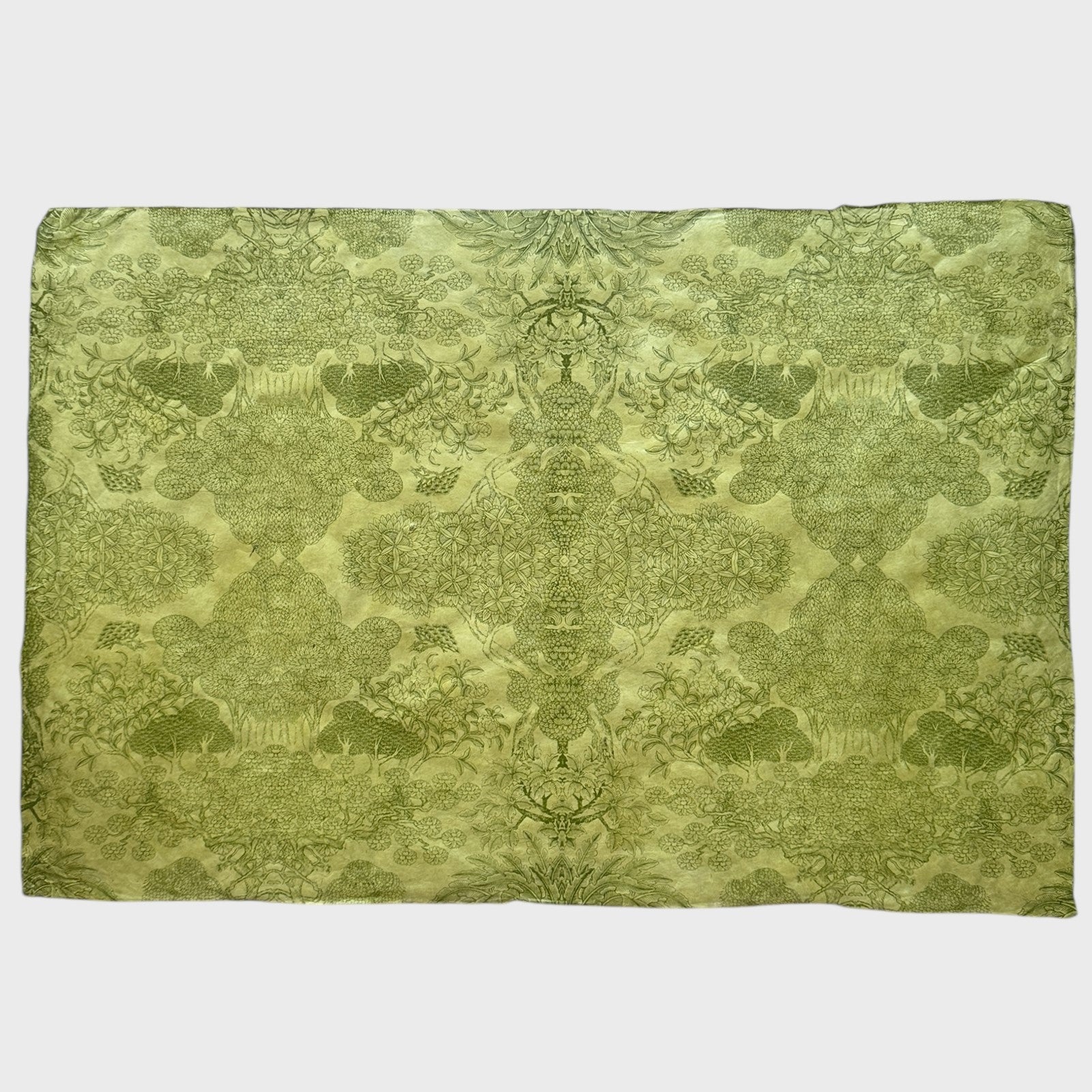 Nepalese handmade decorative lokta paper sheet with a detailed design of trees and flowers in dark green screen printed on a green lokta paper. Full sheet of paper pictured