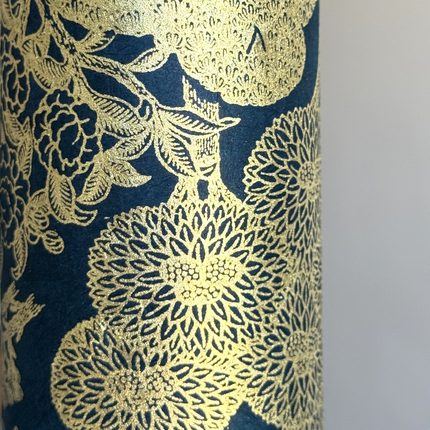 Nepalese handmade decorative lokta paper sheet with a detailed design of trees and flowers in gold metallic screen printed on a midnight blue lokta paper. Close up