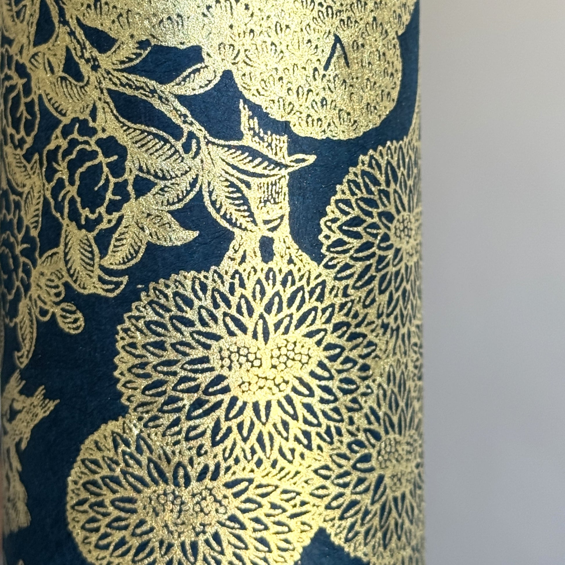 Nepalese handmade decorative lokta paper sheet with a detailed design of trees and flowers in gold metallic screen printed on a midnight blue lokta paper. Close up