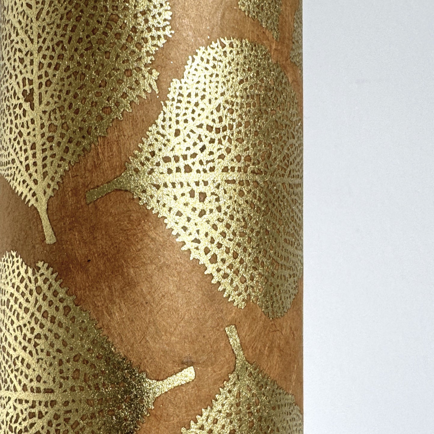 Nepalese handmade decorative lokta paper sheet with a gold metallic leaf pattern screen printed on a tan lokta paper. Close up