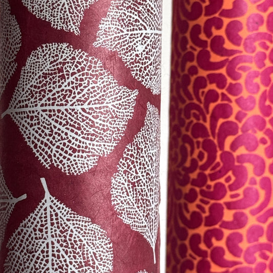 Nepalese handmade decorative lokta paper sheet with a white leaf pattern screen printed on a burgundy lokta paper. Close up