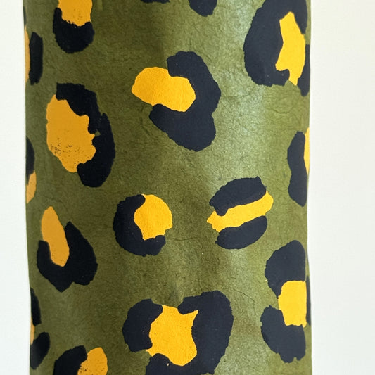 Nepalese handmade decorative lokta paper sheet with an animal print design in two colours, yellow and black, screen printed on a green lokta paper. Close up