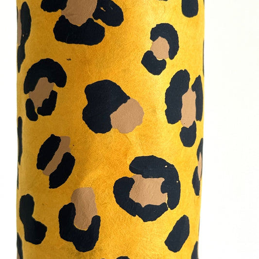 Nepalese handmade decorative lokta paper sheet with an animal print design in two colours, tan and black, screen printed on a yellow lokta paper. Close up