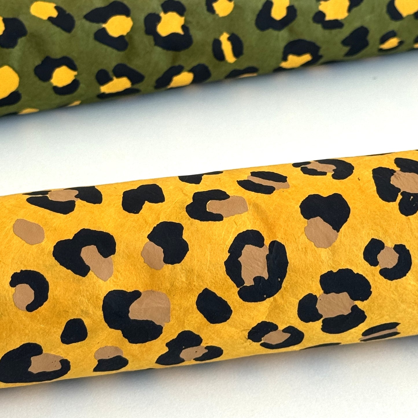 Nepalese handmade decorative lokta paper sheet with an animal print design in two colours, tan and black, screen printed on a yellow lokta paper. Rolled