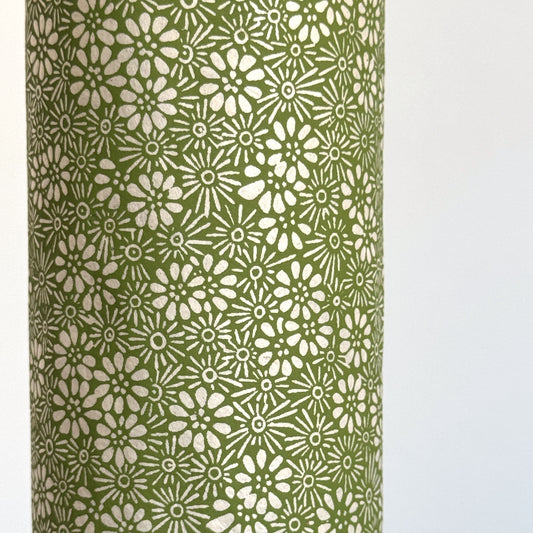 Nepalese handmade decorative lokta paper sheet with a white ditsy floral design screen printed on a green lokta paper. Close up
