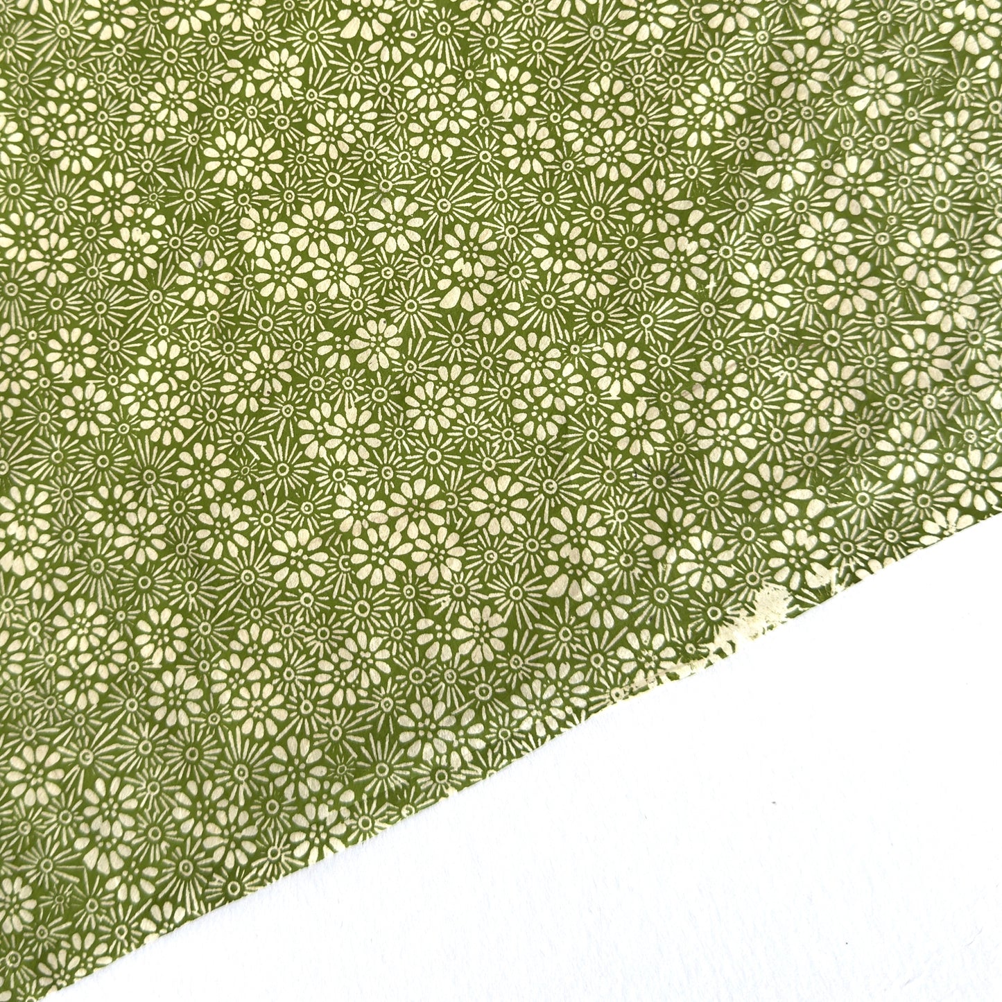 Nepalese handmade decorative lokta paper sheet with a white ditsy floral design screen printed on a green lokta paper.