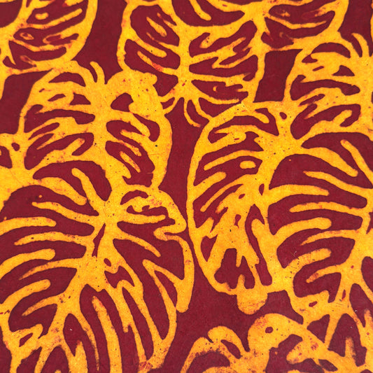 Nepalese handmade decorative lokta paper sheet with a leaf pattern in burgundy red and yellow.  Batik dyed using carved wooden blocks.