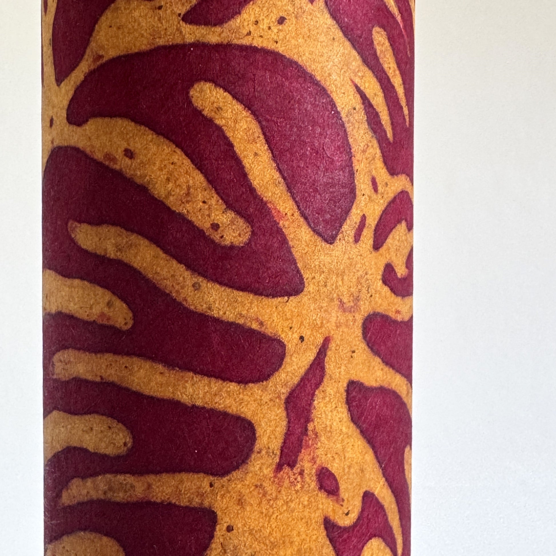 Nepalese handmade decorative lokta paper sheet with a leaf pattern in burgundy red and yellow.  Batik dyed using carved wooden blocks. Close up