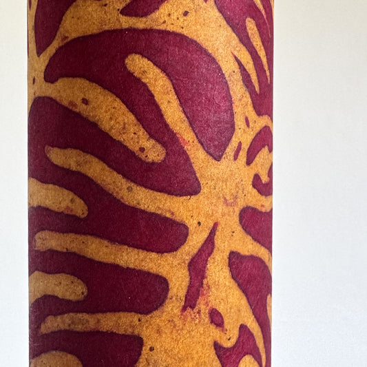 Nepalese handmade decorative lokta paper sheet with a leaf pattern in burgundy red and yellow.  Batik dyed using carved wooden blocks. Close up