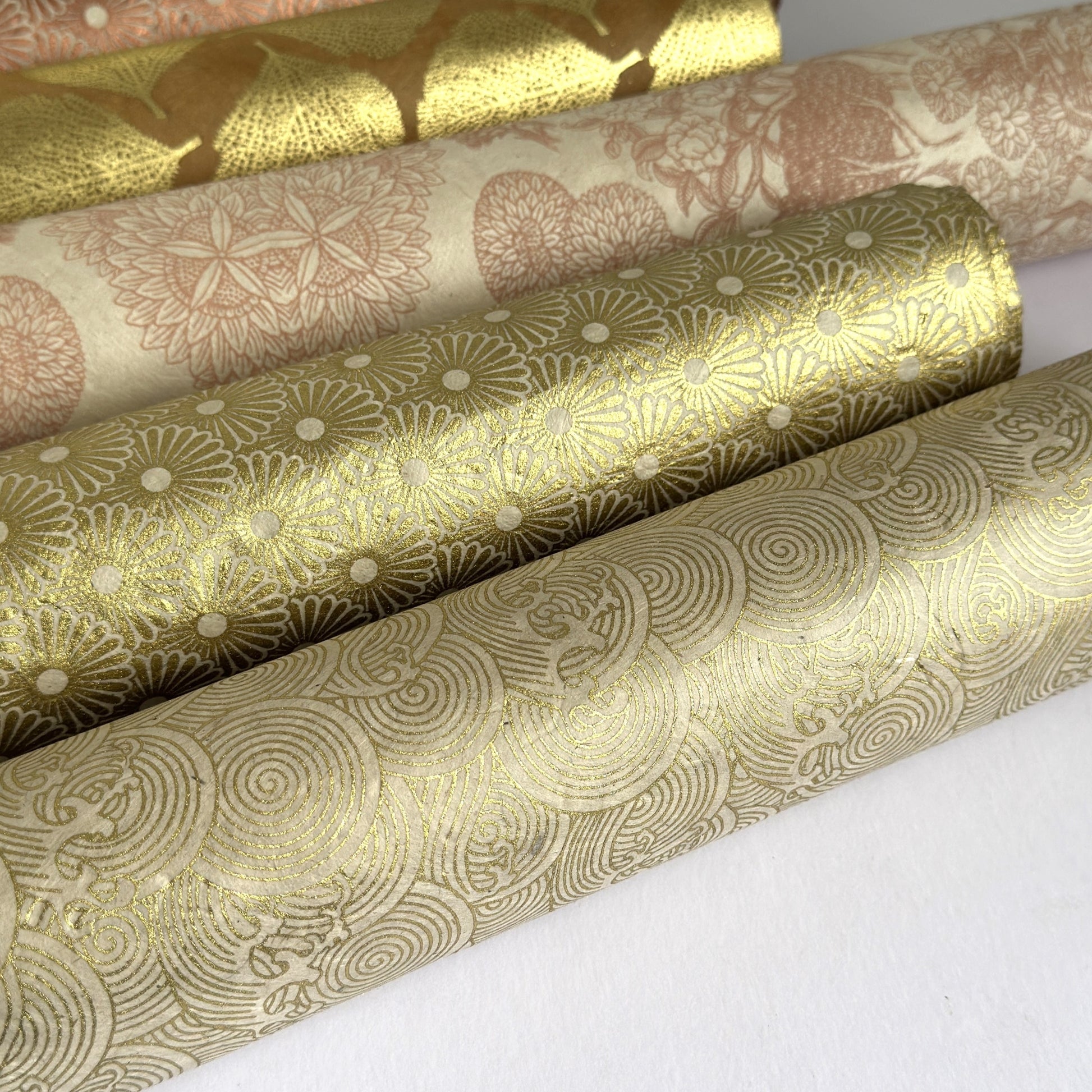 Nepalese handmade decorative lokta paper sheet with a metallic gold wave design screen printed on an ivory lokta paper. Rolled with other gold patterned designs