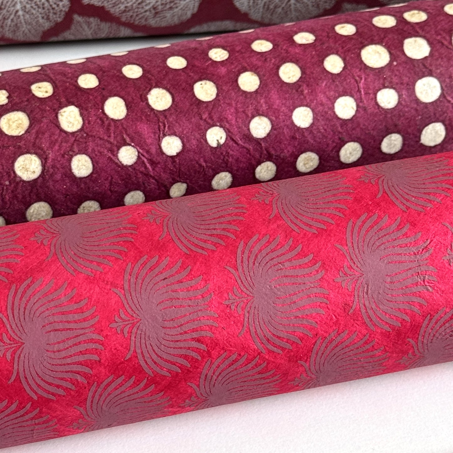 Nepalese handmade decorative lokta paper sheet with a lilac palm leaf design screen printed on a fuchsia pink lokta paper. Rolled