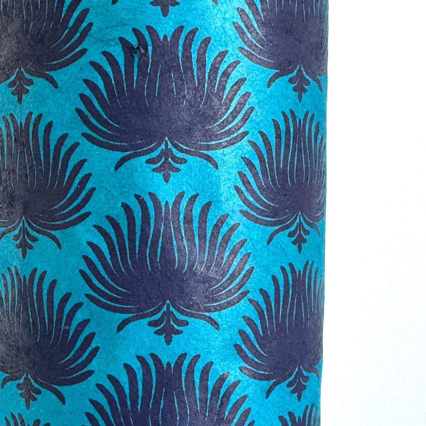 Nepalese handmade decorative lokta paper sheet with an inky blue palm leaf design screen printed on a teal lokta paper. Close up