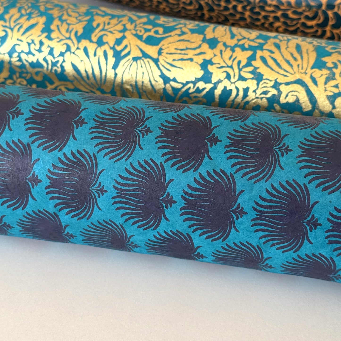 Nepalese handmade decorative lokta paper sheet with an inky blue palm leaf design screen printed on a teal lokta paper.