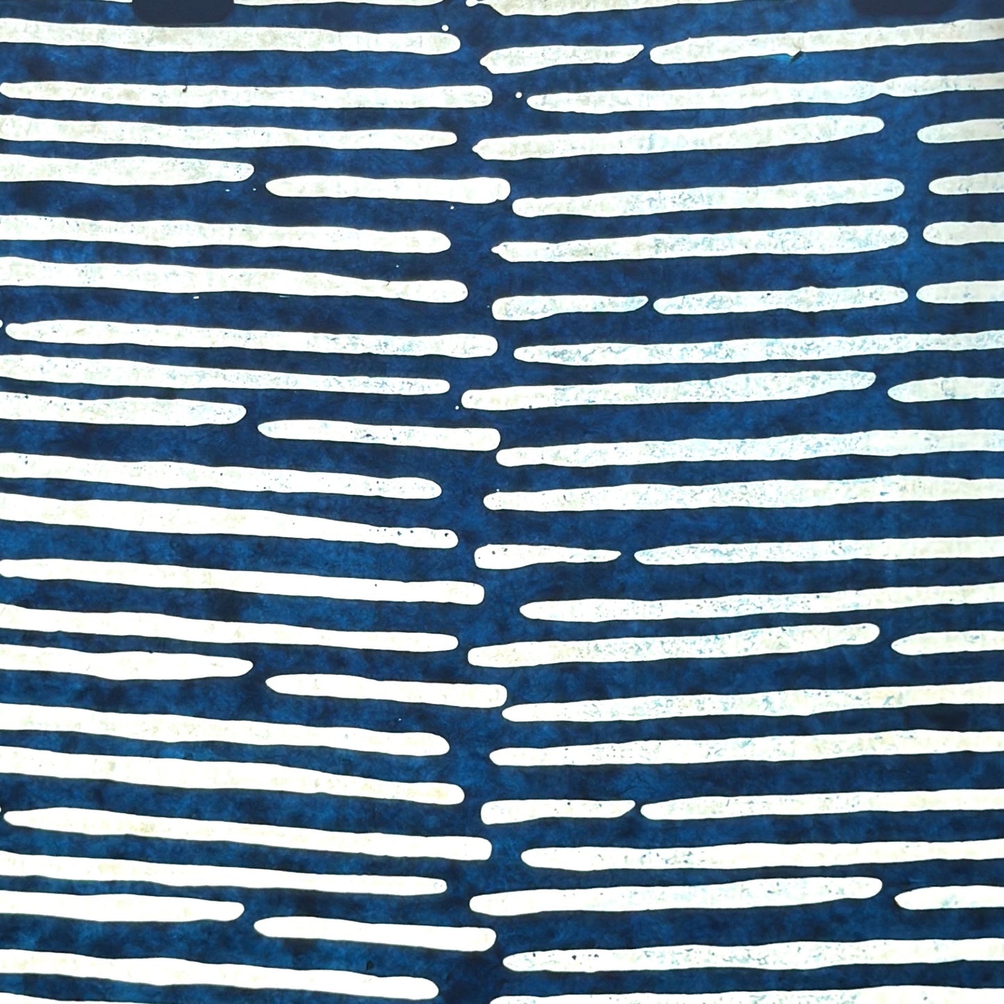 Nepalese handmade decorative lokta paper sheet with a stripe pattern in petrol blue and white.  Batik dyed using carved wooden blocks. Pictured next to light to show the translucent nature