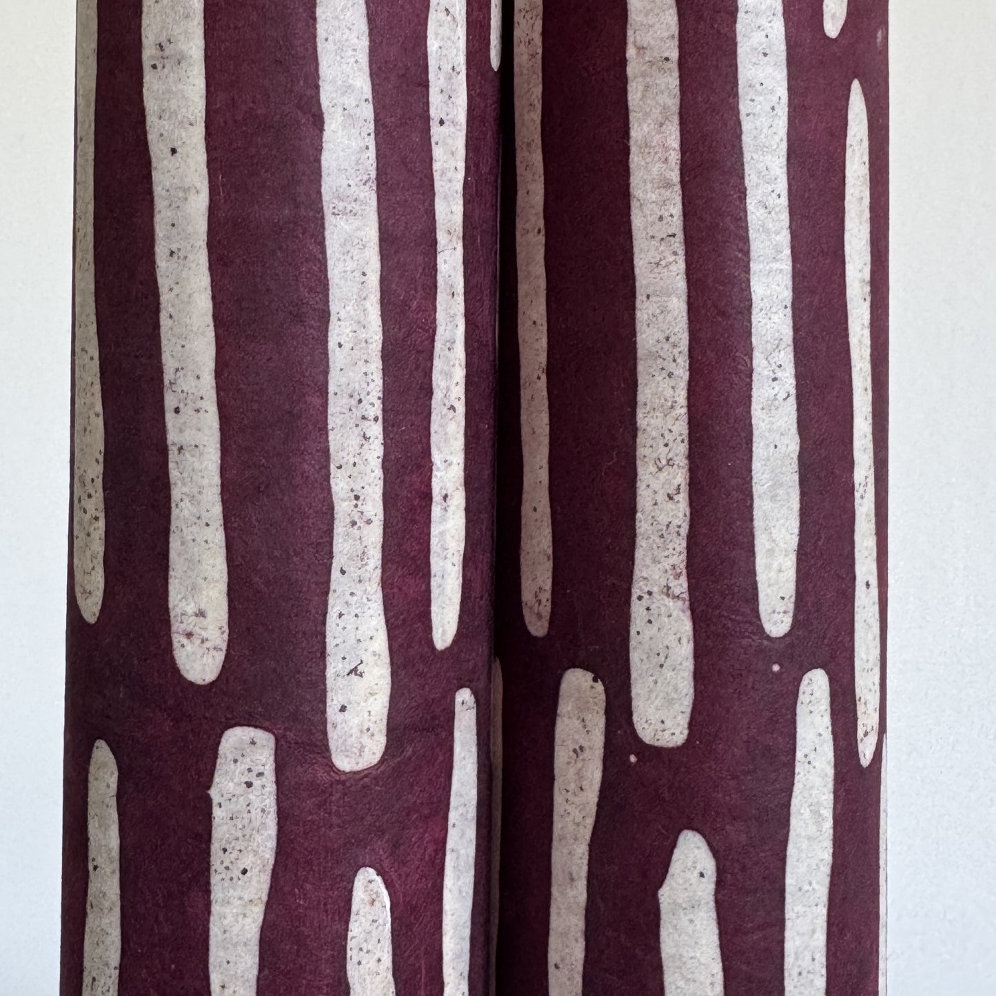 Nepalese handmade decorative lokta paper sheet with a stripe pattern in burgundy and white.  Batik dyed using carved wooden blocks. close up