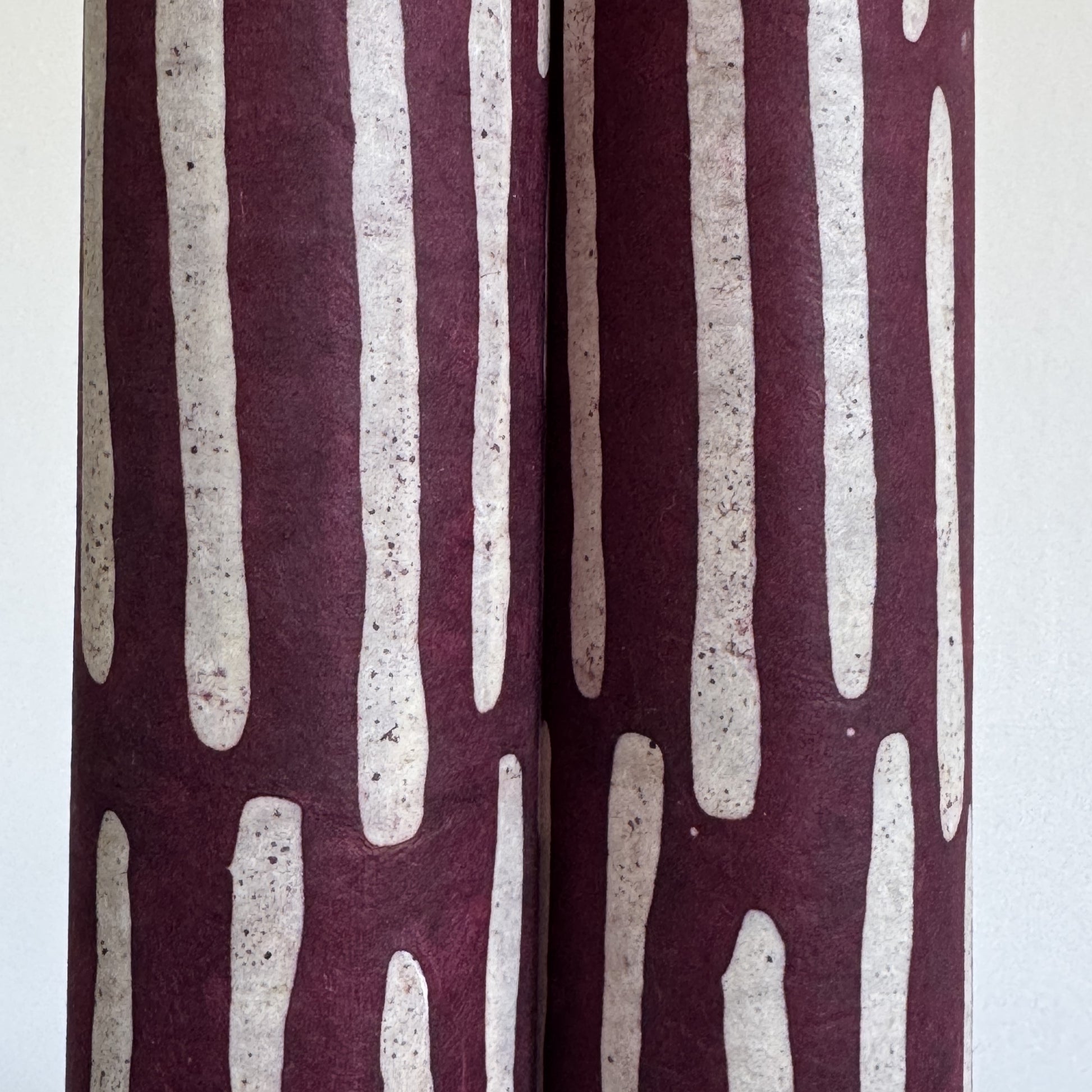 Nepalese handmade decorative lokta paper sheet with a stripe pattern in burgundy and white.  Batik dyed using carved wooden blocks. close up