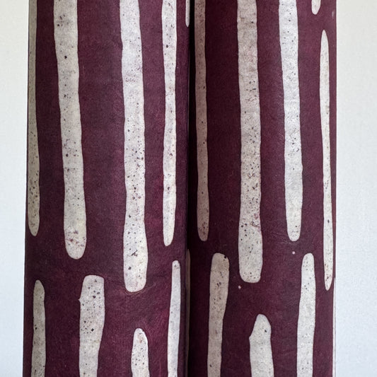 Nepalese handmade decorative lokta paper sheet with a stripe pattern in burgundy and white.  Batik dyed using carved wooden blocks. close up