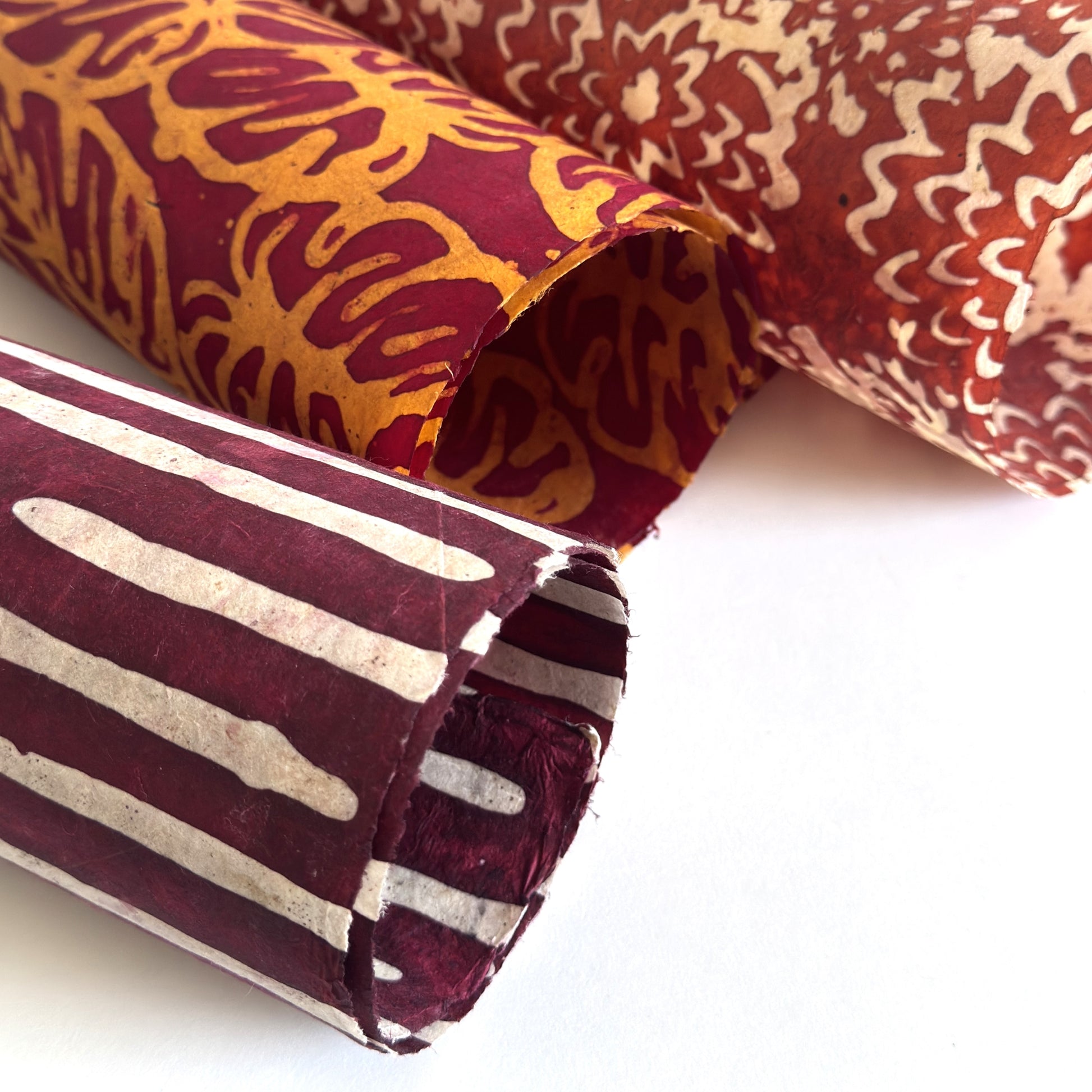 Nepalese handmade decorative lokta paper sheet with a stripe pattern in burgundy and white.  Batik dyed using carved wooden blocks. Rolled