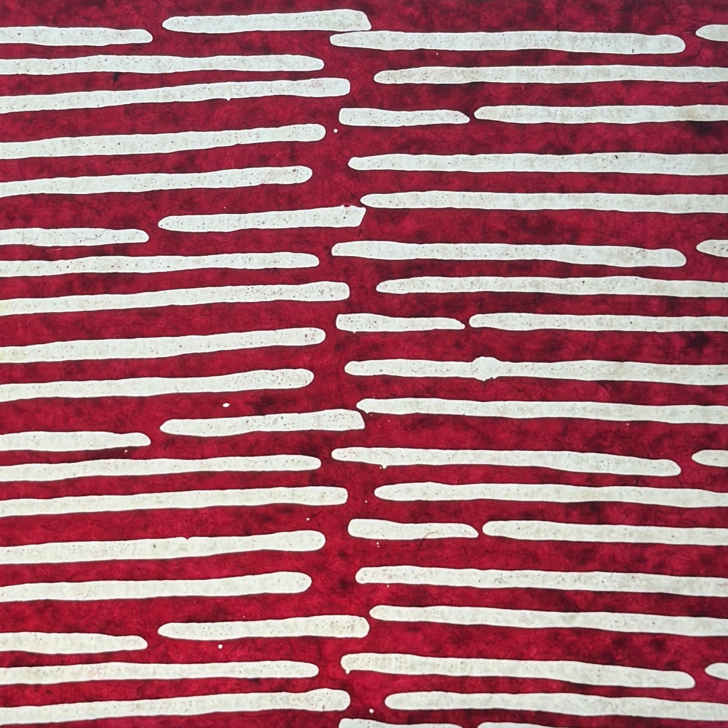 Nepalese handmade decorative lokta paper sheet with a stripe pattern in burgundy and white.  Batik dyed using carved wooden blocks. Pictured next to light to show translucent nature.