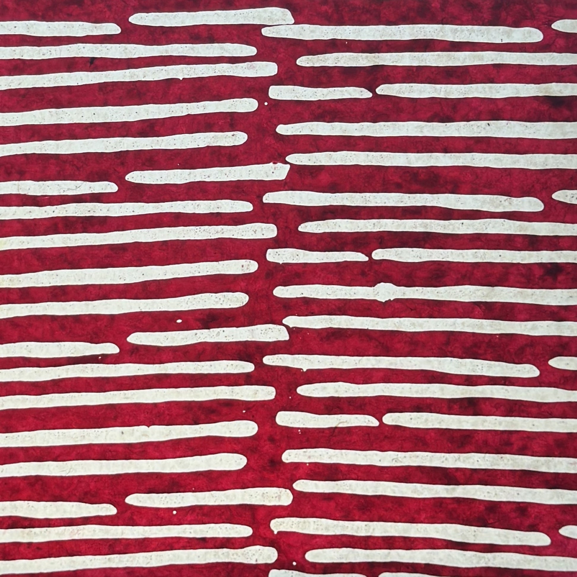 Nepalese handmade decorative lokta paper sheet with a stripe pattern in burgundy and white.  Batik dyed using carved wooden blocks. Pictured next to light to show translucent nature.