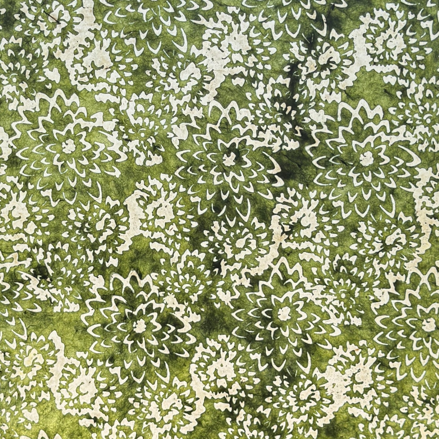 Nepalese handmade decorative lokta paper sheet with a floral pattern in green and cream. Batik dyed using carved wooden blocks. Photographed with light to show the translucent nature