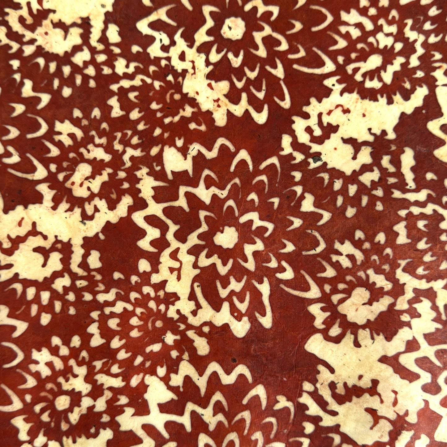 Nepalese handmade decorative lokta paper sheet with a floral pattern in rust and cream.  Batik dyed using carved wooden blocks.