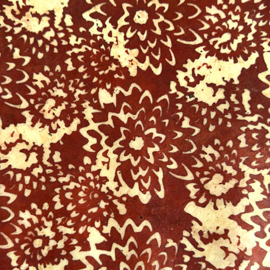Nepalese handmade decorative lokta paper sheet with a floral pattern in rust and cream.  Batik dyed using carved wooden blocks.