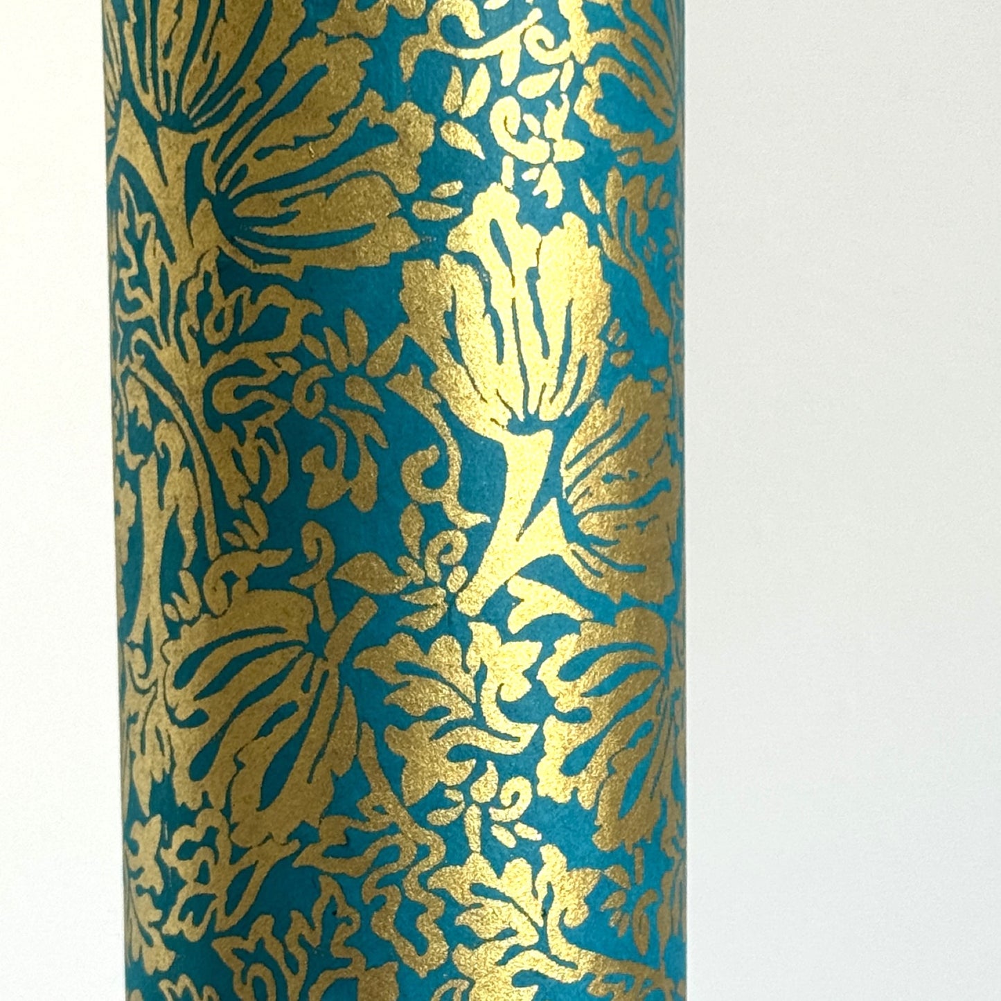 Nepalese handmade decorative lokta paper sheet with a metallic gold tulip design screen printed on a teal lokta paper. Close up
