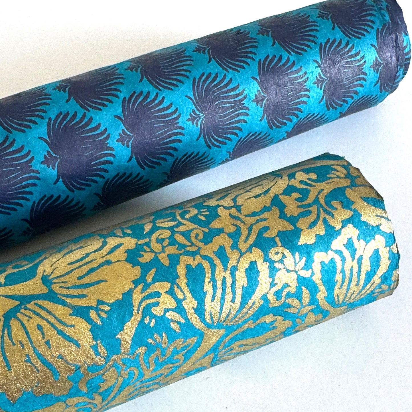 Nepalese handmade decorative lokta paper sheet with a metallic gold tulip design screen printed on a teal lokta paper. Rolled