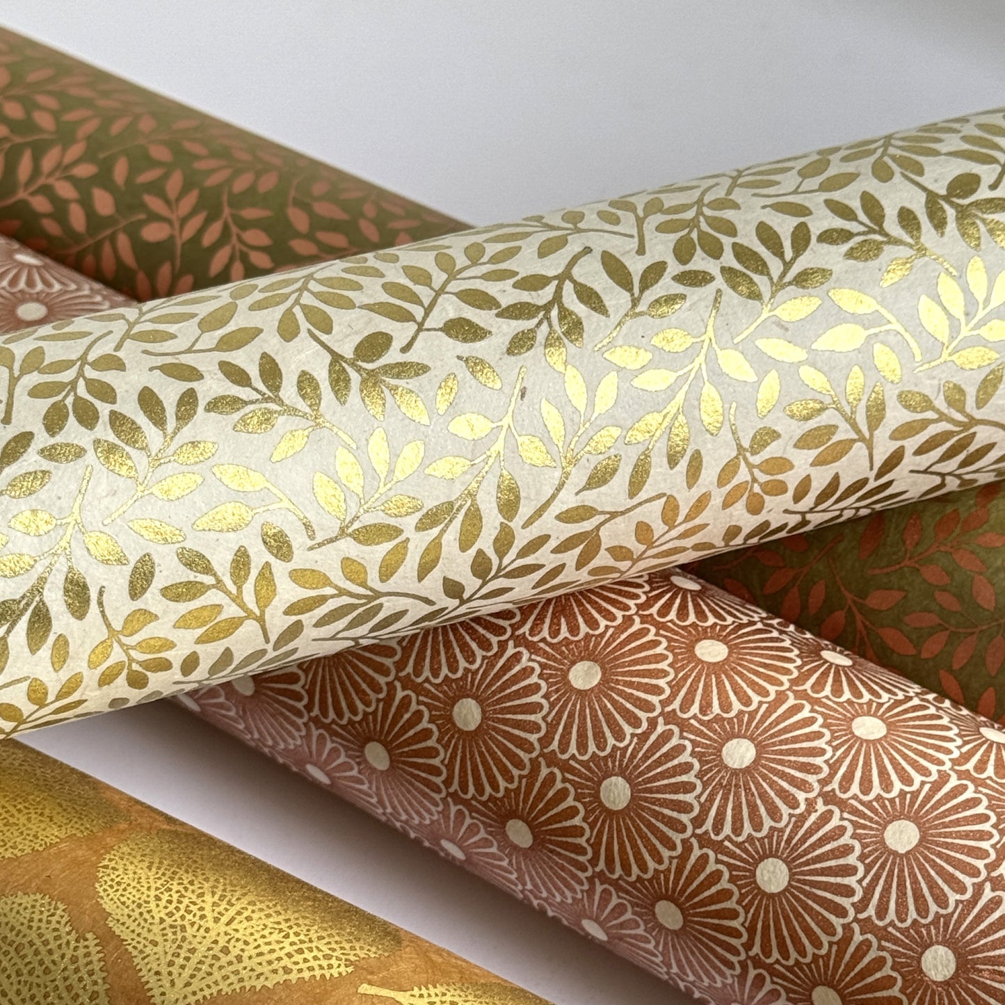 Nepalese handmade decorative lokta paper sheet with a metallic gold willow design screen printed on an ivory lokta paper. Rolled with other designs