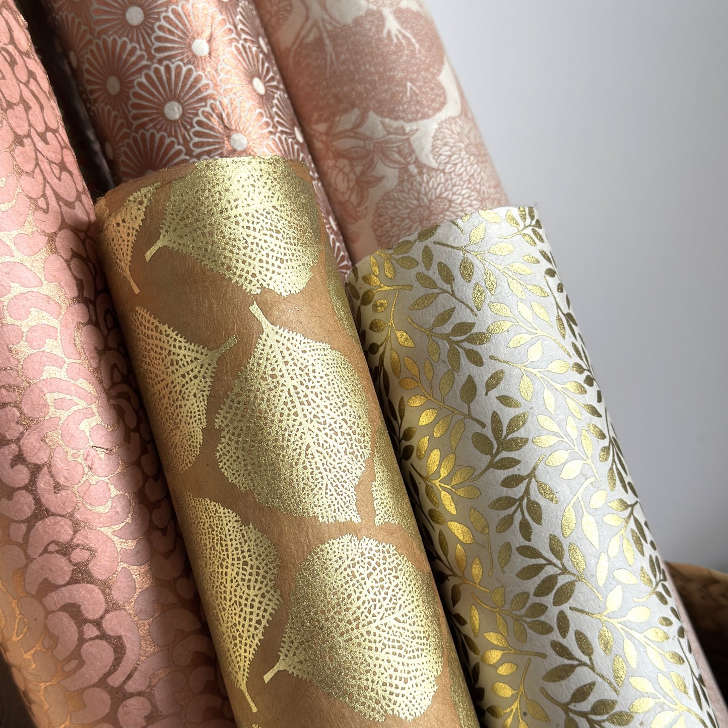 Nepalese handmade decorative lokta paper sheet with a metallic gold willow design screen printed on an ivory lokta paper. Rolled with other designs