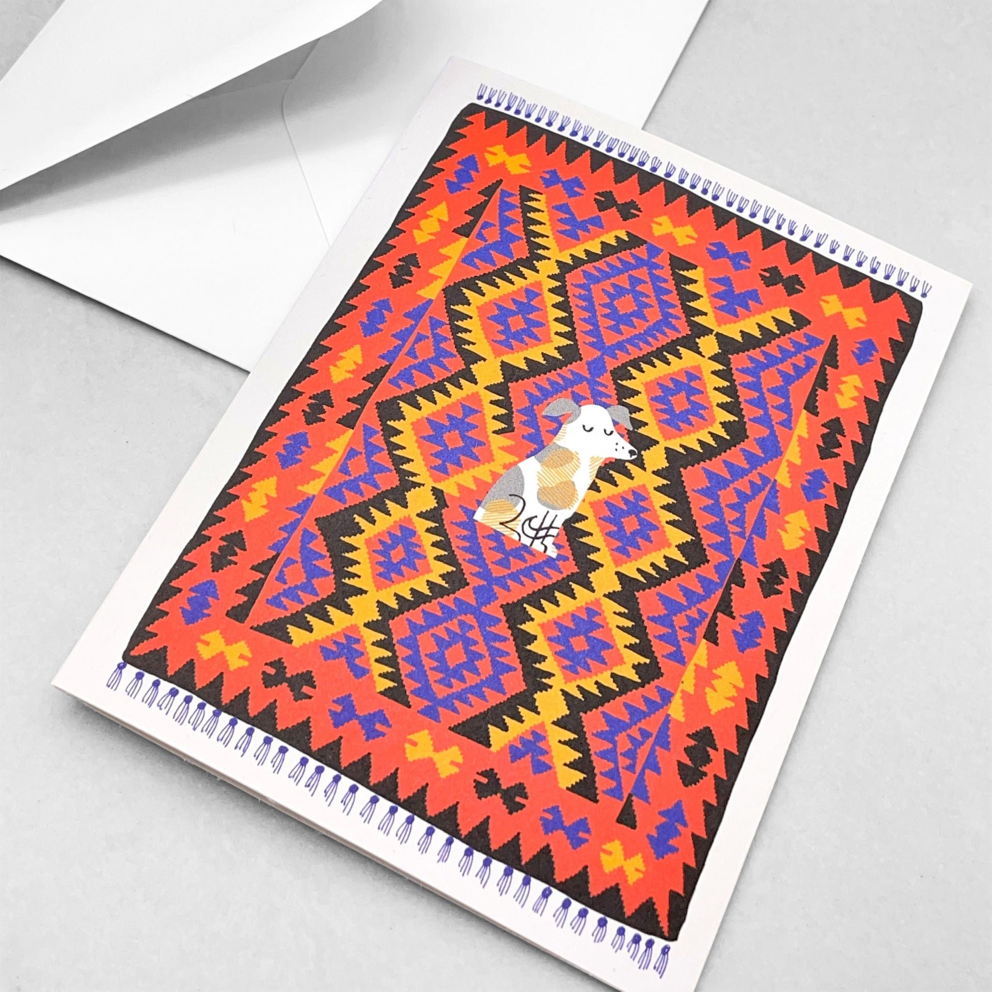 Small greetings card of a drawing of a little terrier dog sitting in the middles of a red, blue and yellow oriental rug by Lisa Jones Studio