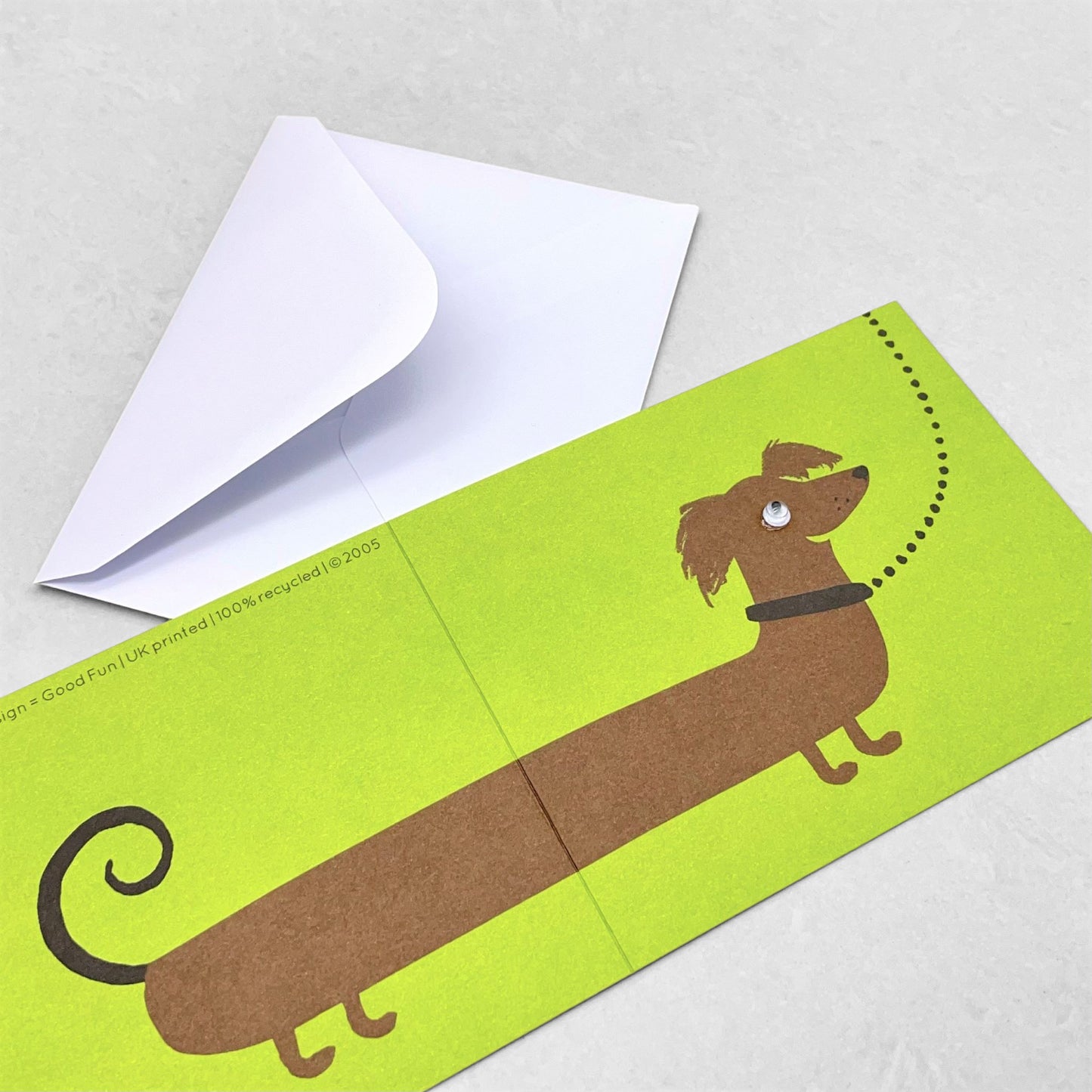 Small greetings card of a drawing of a brown sausage dog on a lead with lime green backdrop by Lisa Jones Studio