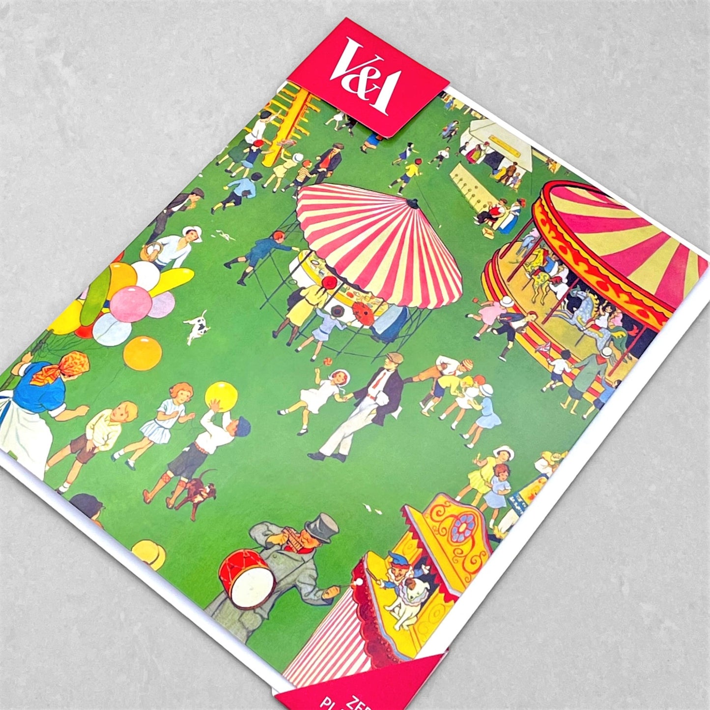 greetings card showing a scene from a country fair with carousel, punch and judy and balloon seller