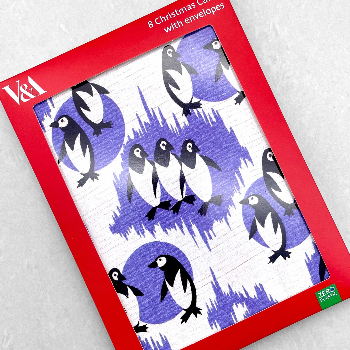 greetings card showing a repeat pattern of black and white penguins with patterned deep lavender backdrop