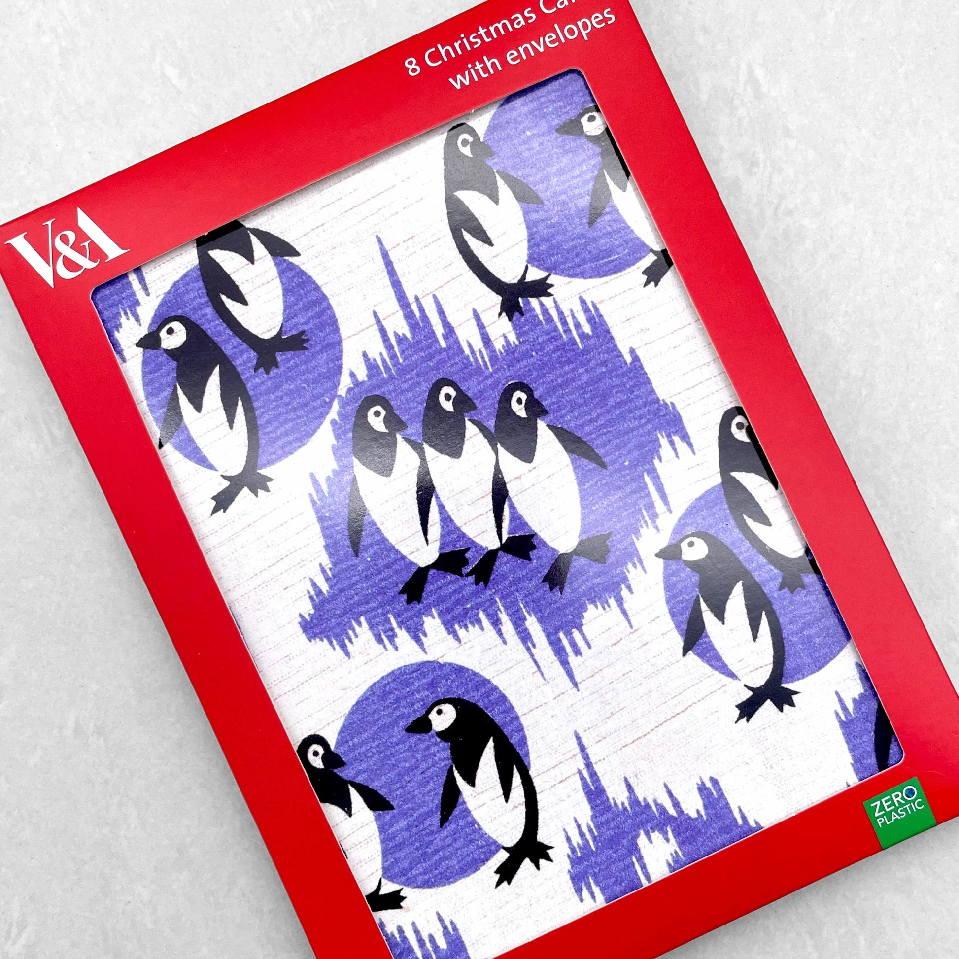 greetings card showing a repeat pattern of black and white penguins with patterned deep lavender backdrop