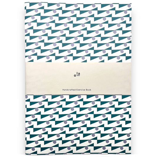 slimline exercise book with plain pages by Ola Studio, cover is a geometric repeat design in teal and lilac on a white background. Pictured with branded presentation band