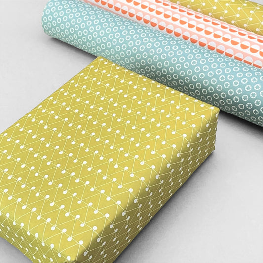 wrapping paper with abstract triangle and dot pattern in mustard and white by Ola Studio