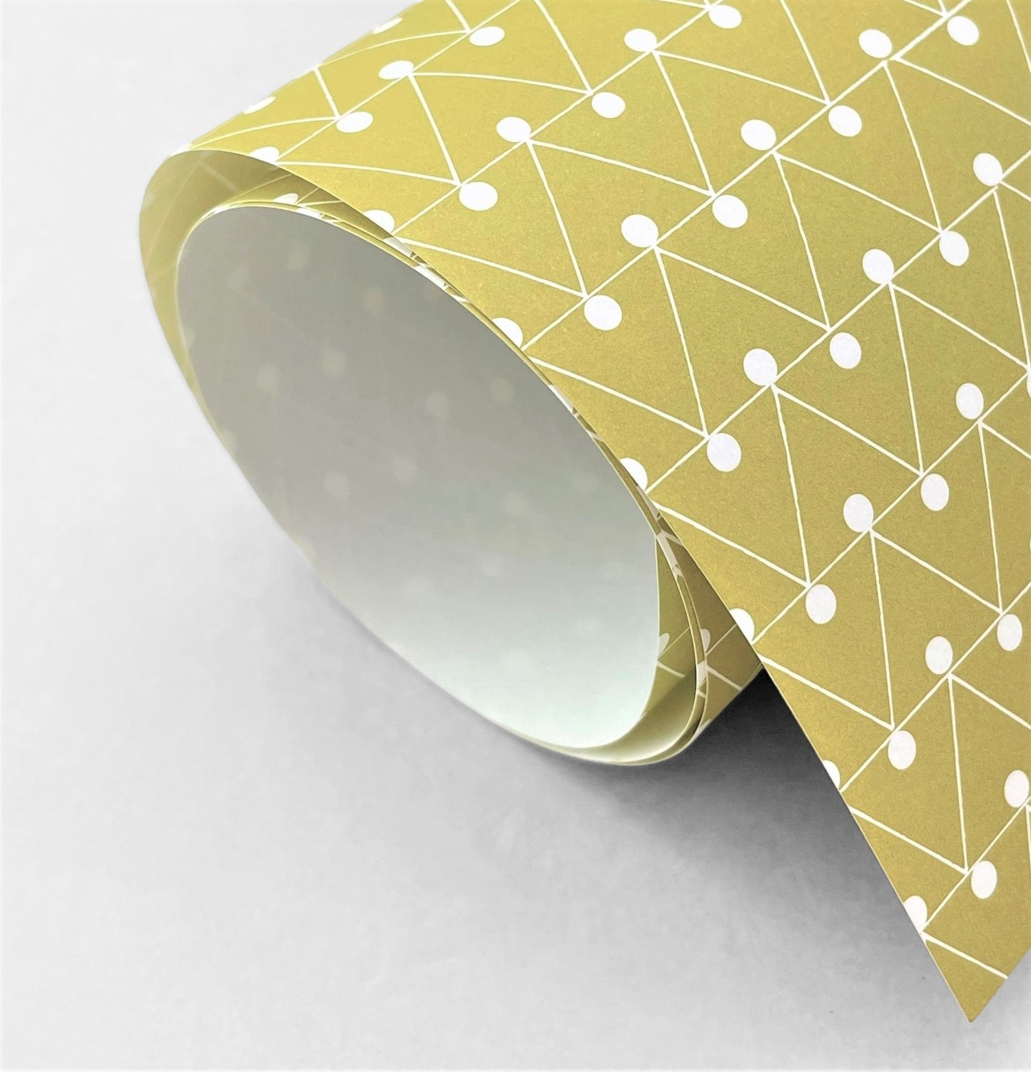 wrapping paper with abstract triangle and dot pattern in mustard and white by Ola Studio