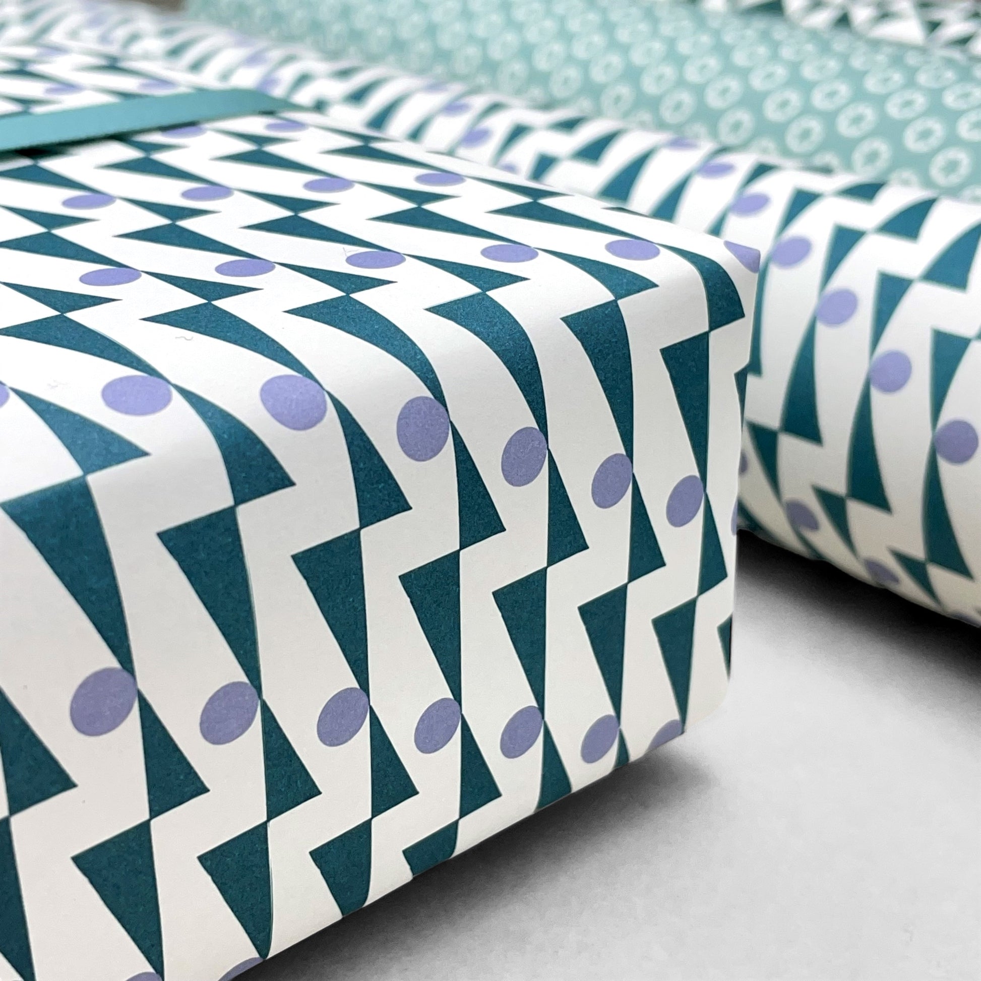 wrapping paper with abstract triangle and dot pattern in blue and lilac by Ola Studio
