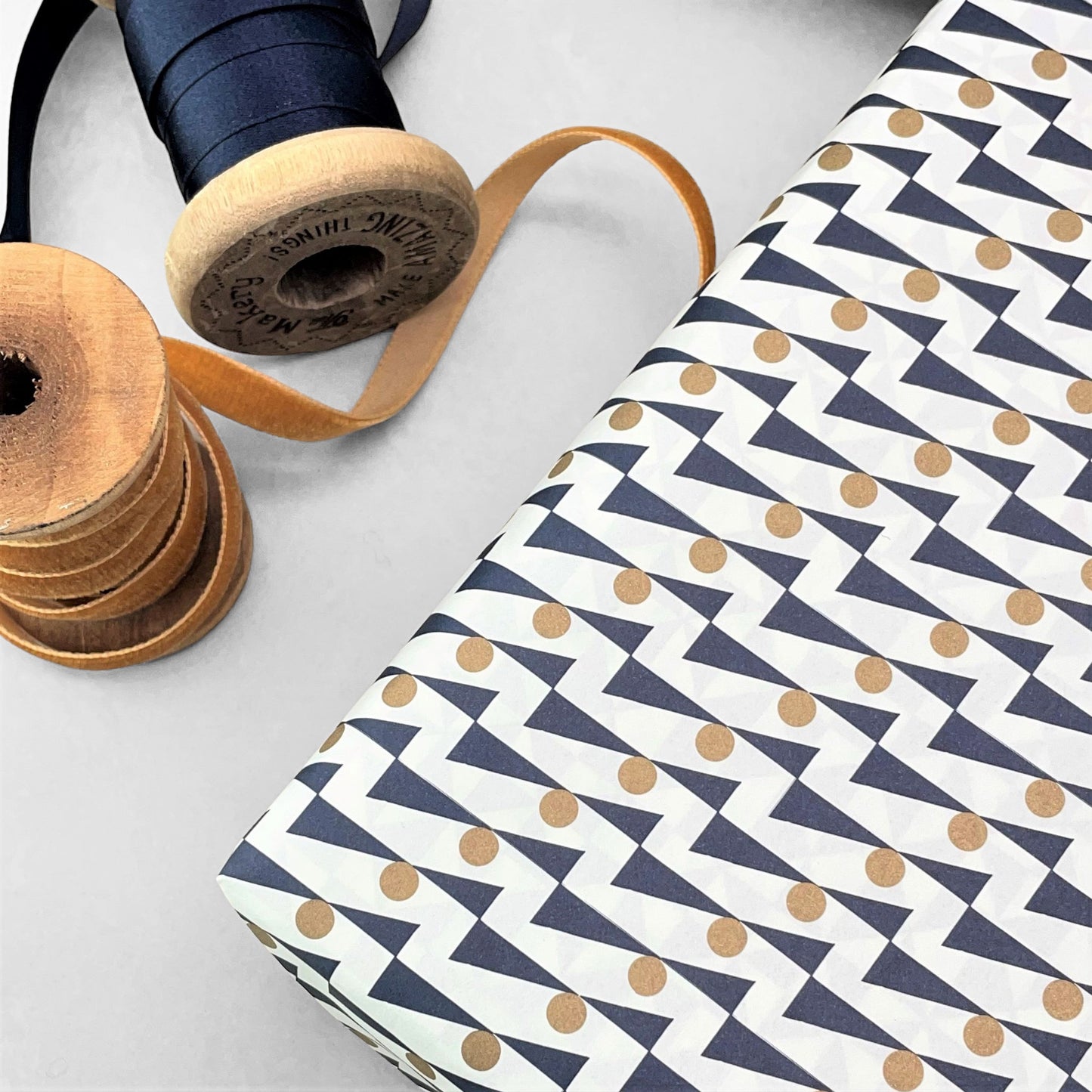 wrapping paper with abstract triangle and dot pattern in navy and gold on a white background by Ola Studio