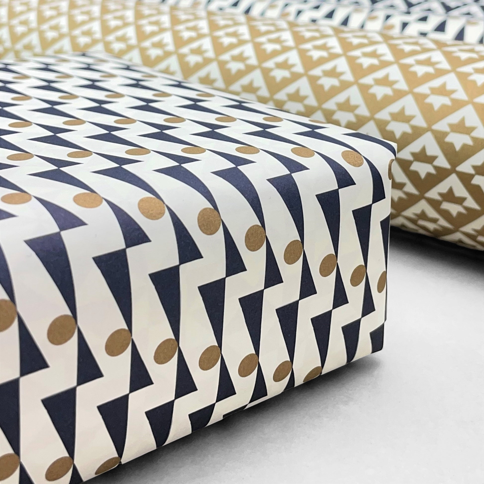 wrapping paper with abstract triangle and dot pattern in navy and gold on a white background by Ola Studio