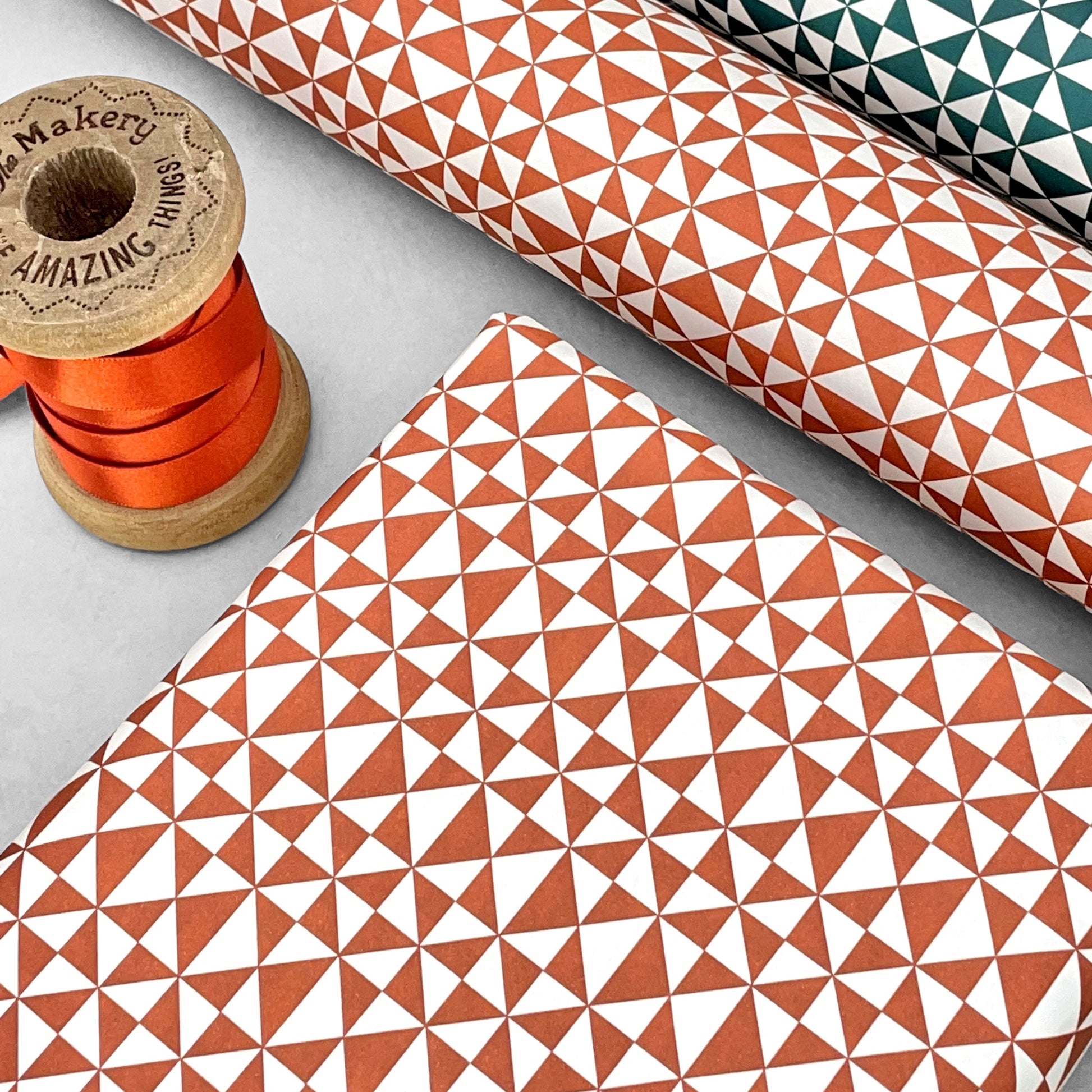 wrapping paper with an abstract triangle pattern in brick red and white by Ola Studio