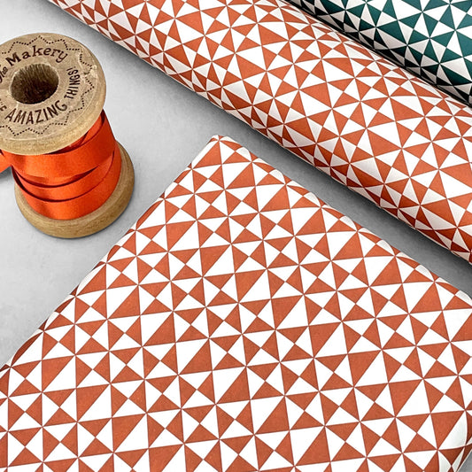wrapping paper with an abstract triangle pattern in brick red and white by Ola Studio
