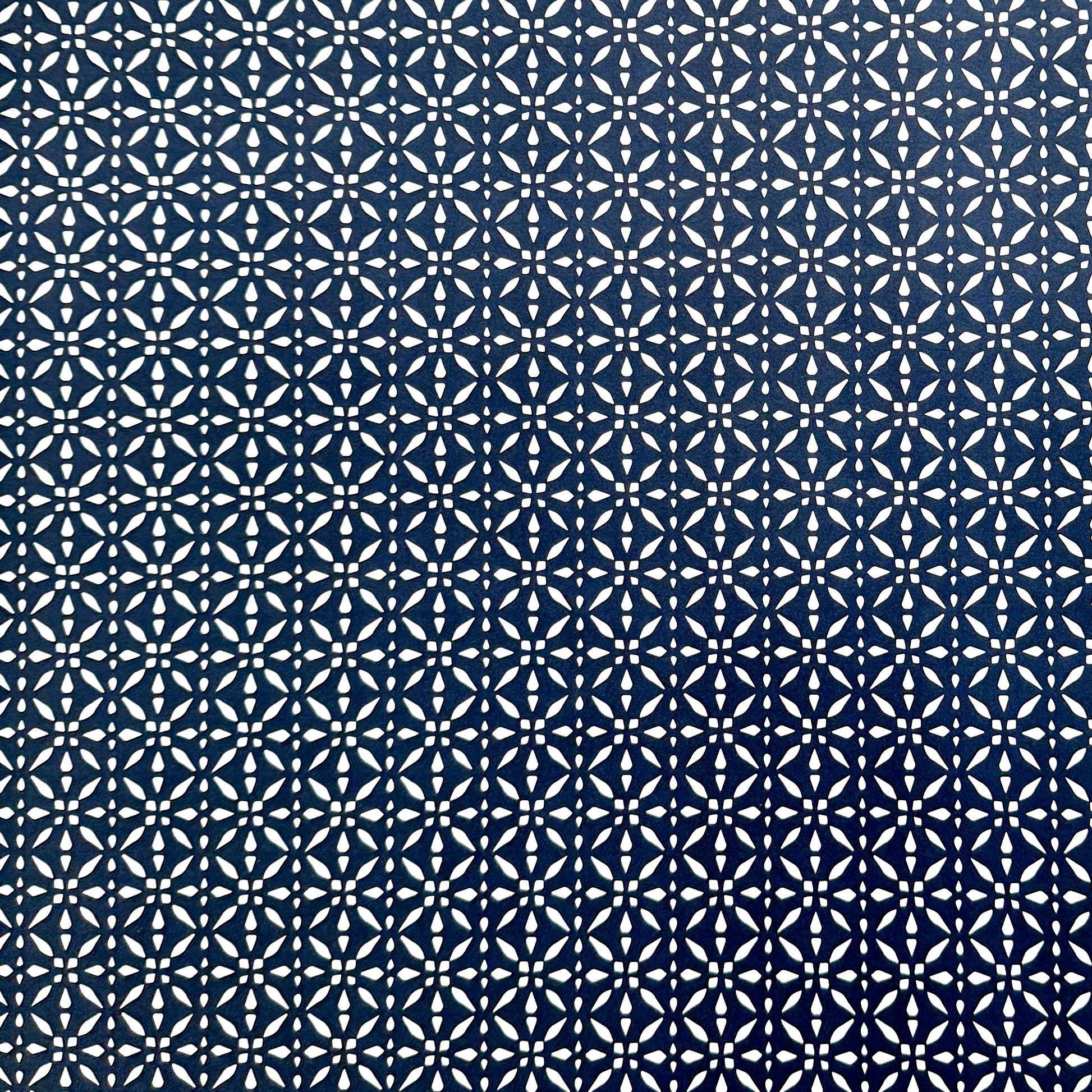 wrapping paper by Otto Editions with a cut-out design in white on an indigo blue background.