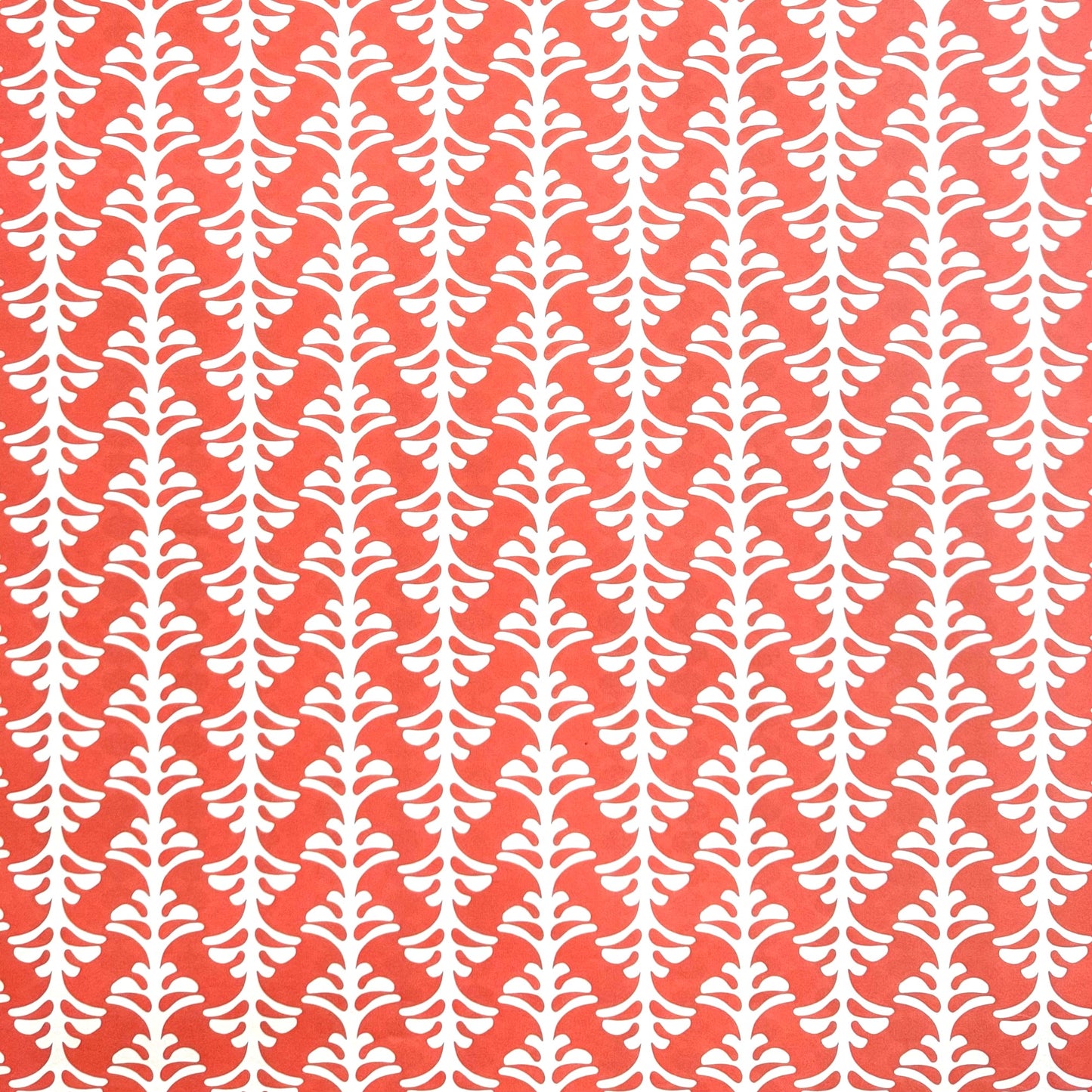 wrapping paper by Otto Editions with a cut-out palm design in white on a coral pink background.