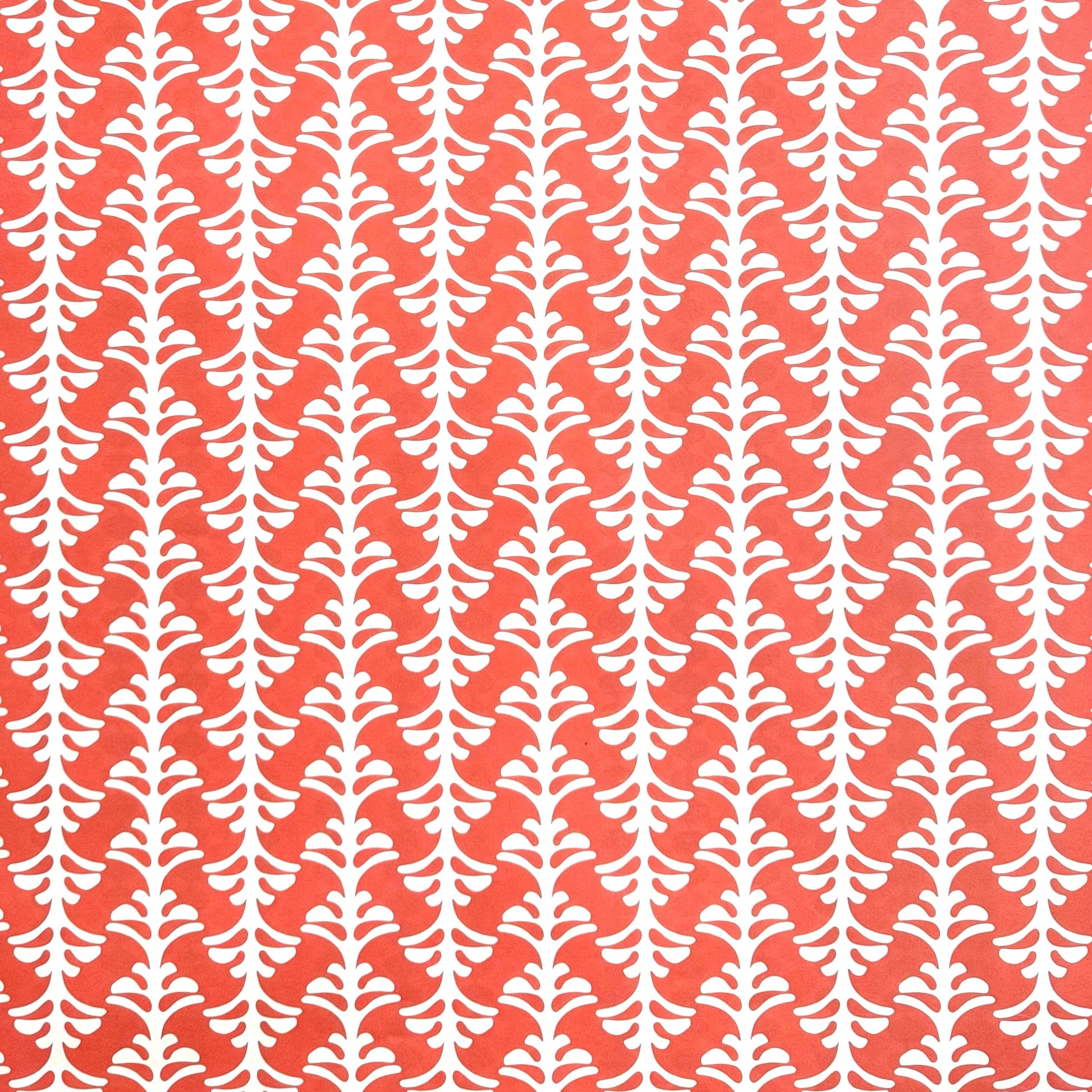 wrapping paper by Otto Editions with a cut-out palm design in white on a coral pink background.